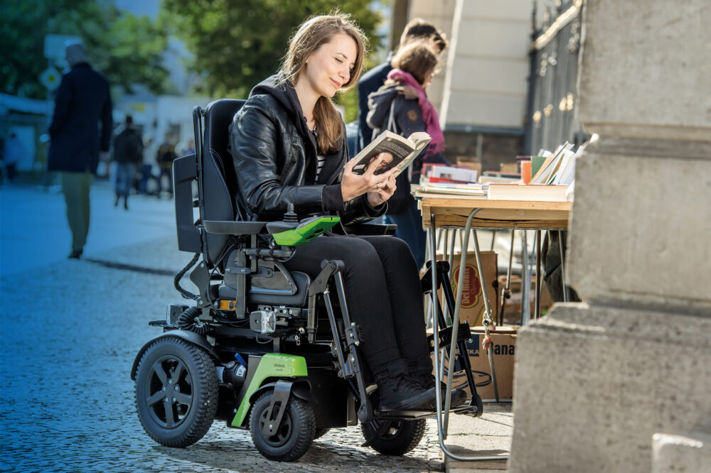 woman reading a book in a green powered wheelchair