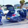 Couple loading foldable mobility scooter into a car boot